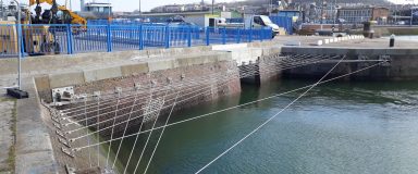 Vue d'un bassin portuaire avec un dispositif de filins accrochés aux murs au-dessus de l'eau pour empêcher le braconnage par le pêche.