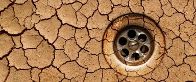 Drought - dry crackled ground with water outflow (view from top)